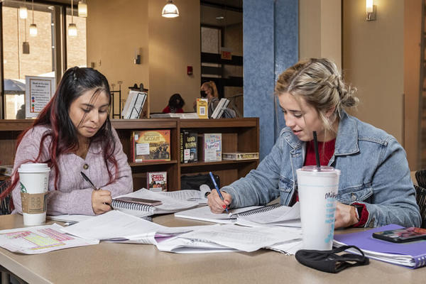 photo of two students sitting at a table working on classwork