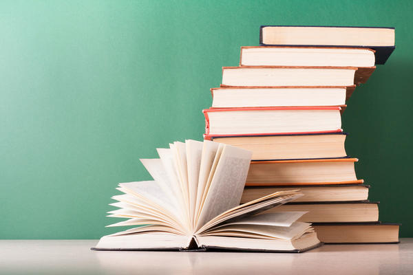 photo of an open book in front of a stack of books