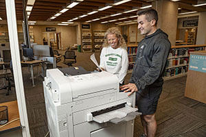 Library staff demonstrating printer use to student