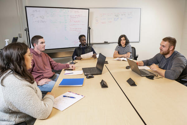 Students collaborating at a table in a library group study room