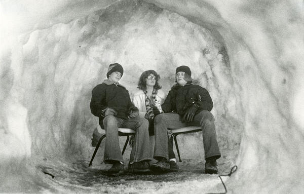 Three people sitting on chairs inside an igloo