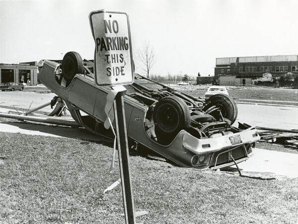 Aftermath of the Xenia tornado showing a car flipped onto its roof next to a "No Parking" sign.