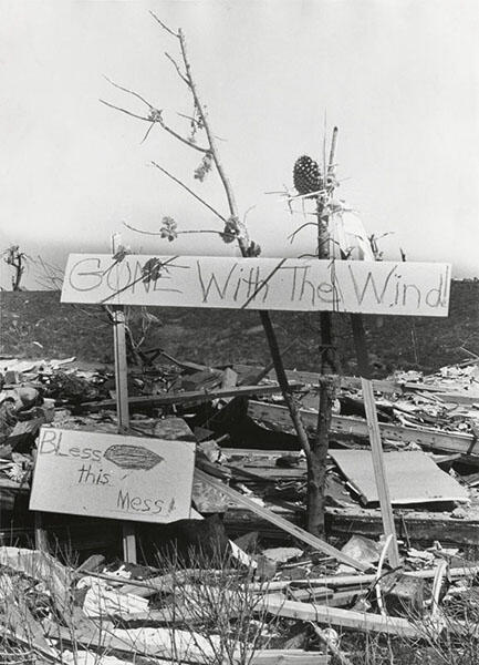 A sign that reads "Gone with the Wind" amid tornado devastation..