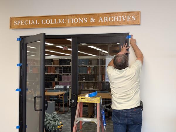A man installing doors under a sign that reads "Special Collections & Archives."