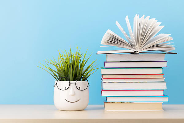 Stack of books beside a plant 