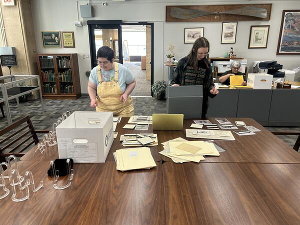Two interns sorting archival material on a table.