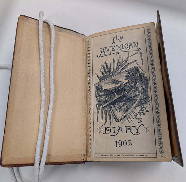 A diary opened to the cover page with the words "The American Diary 1903."