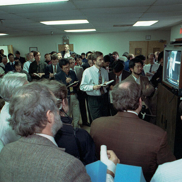 A group of journalists watching a televisions showing President Bill Clinton.