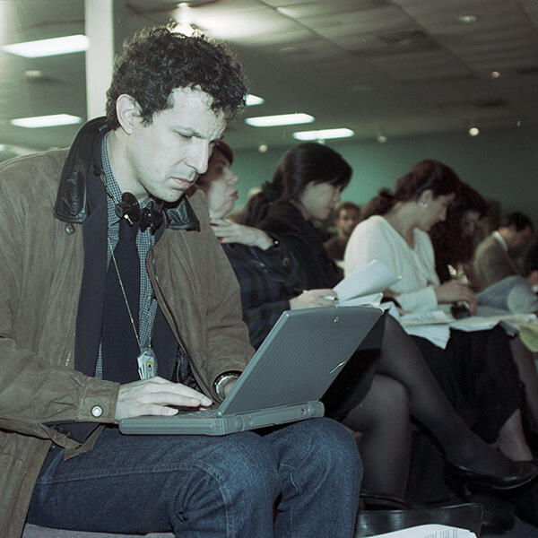 A man seated with a laptop on his lap.