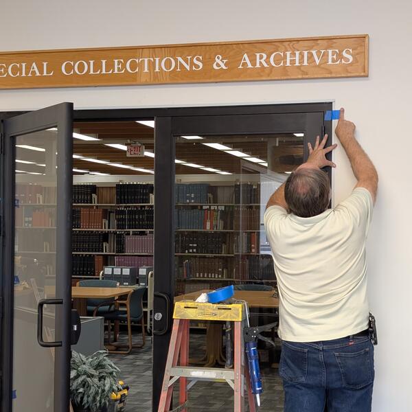 A man installing doors under a sign that reads "Special Collections & Archives."