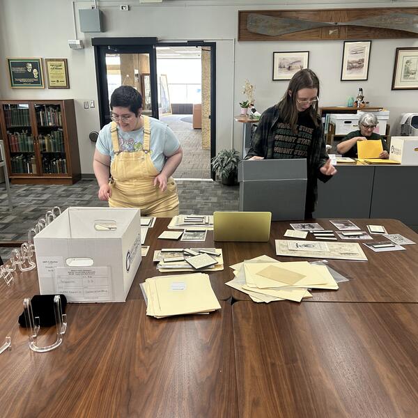 Two interns sorting archival material on a table.