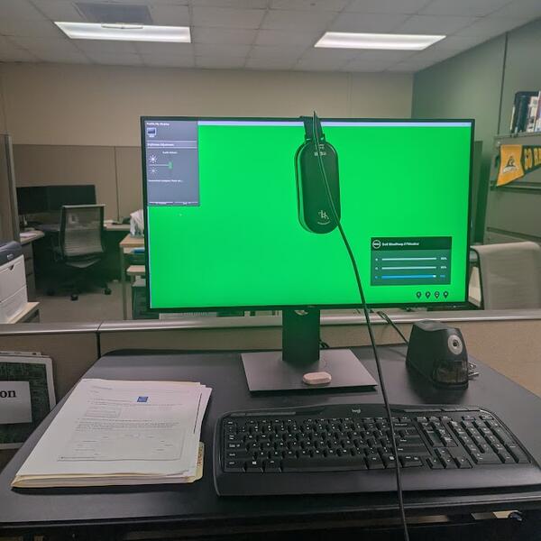 A green computer screen with a calibrator on the monitor.