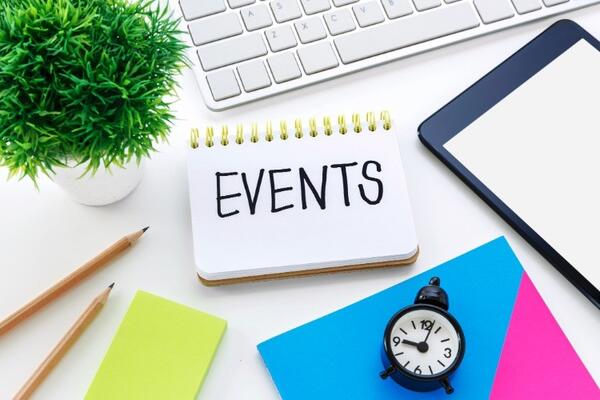 Image of a desktop containing a keyboard, watch, plant, pencils, paper, and a notebook with the word "Events" written in bold font