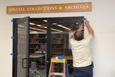 A man installing doors under a sign that reads "Special Collections & Archives."