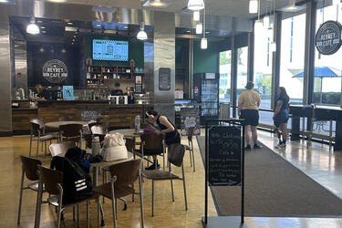 The ReyRey counter with staff working and customers standing in line and seated at a table.