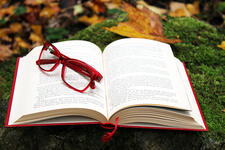 Image of open book with eyeglasses on top